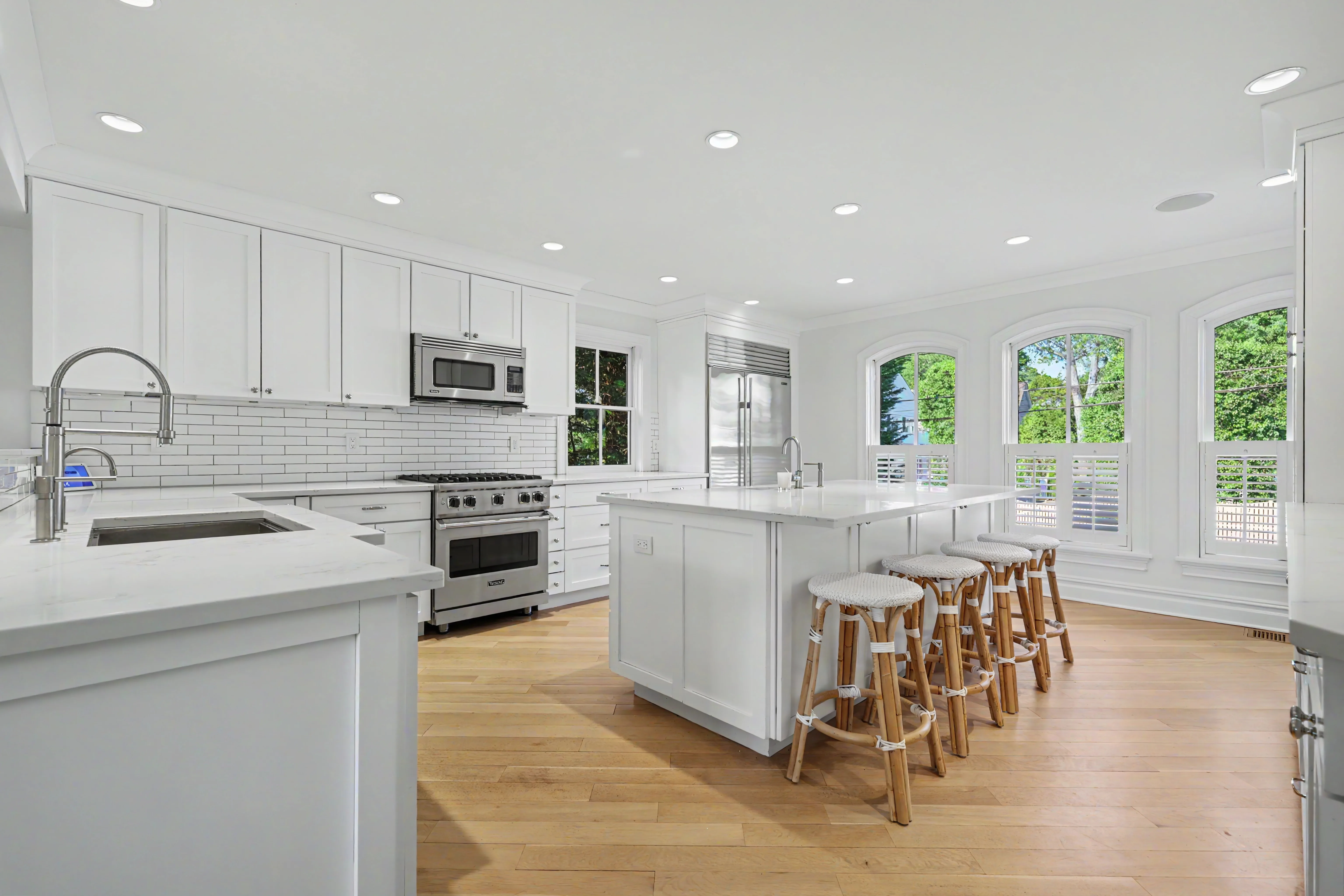 Kitchen with center island, bar stools, and stainless appliances — natural light through arched windows, Westchester County NY