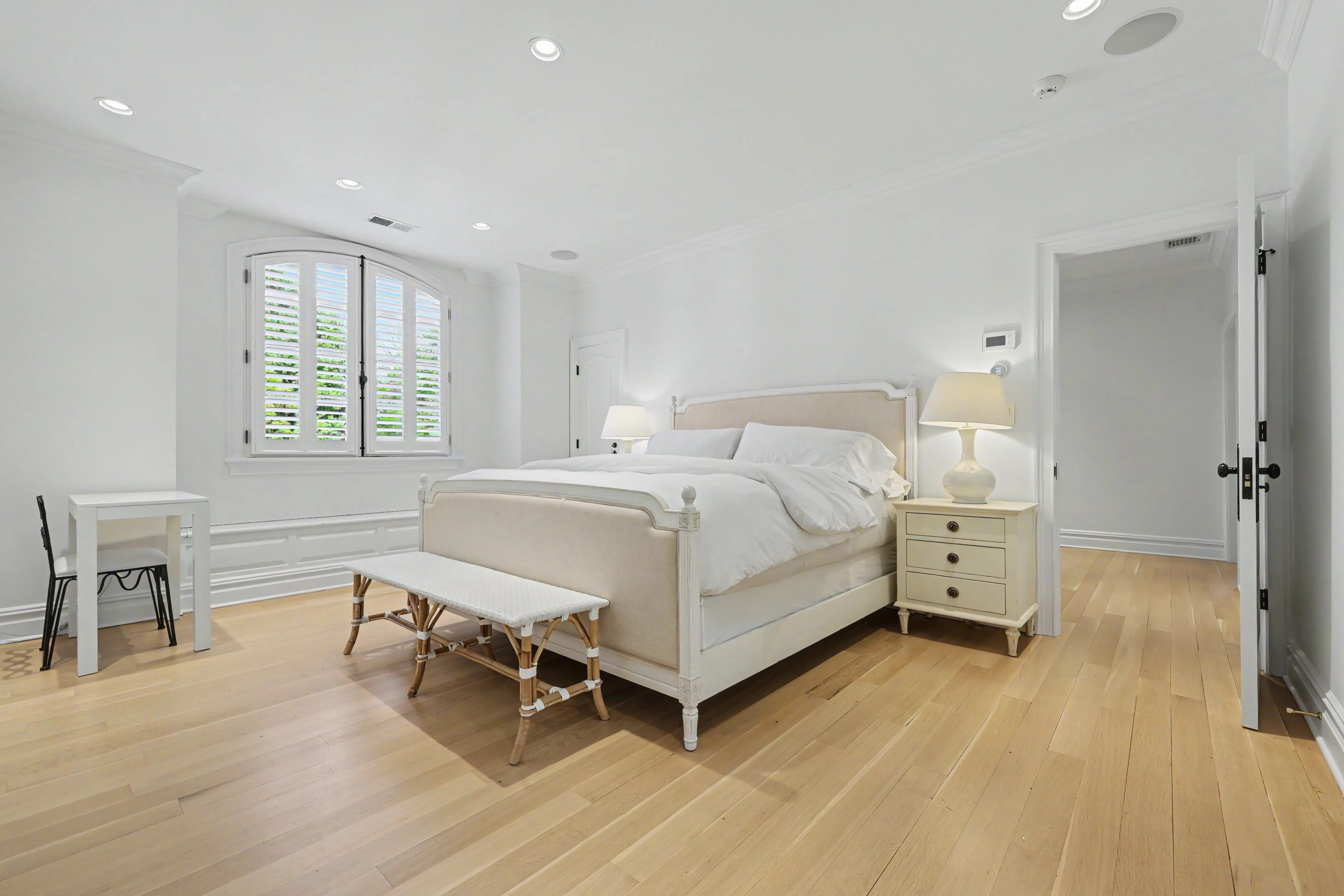 Primary bedroom with plantation shutters and wide-plank hardwood floors — bright listing interior, Westchester County NY
