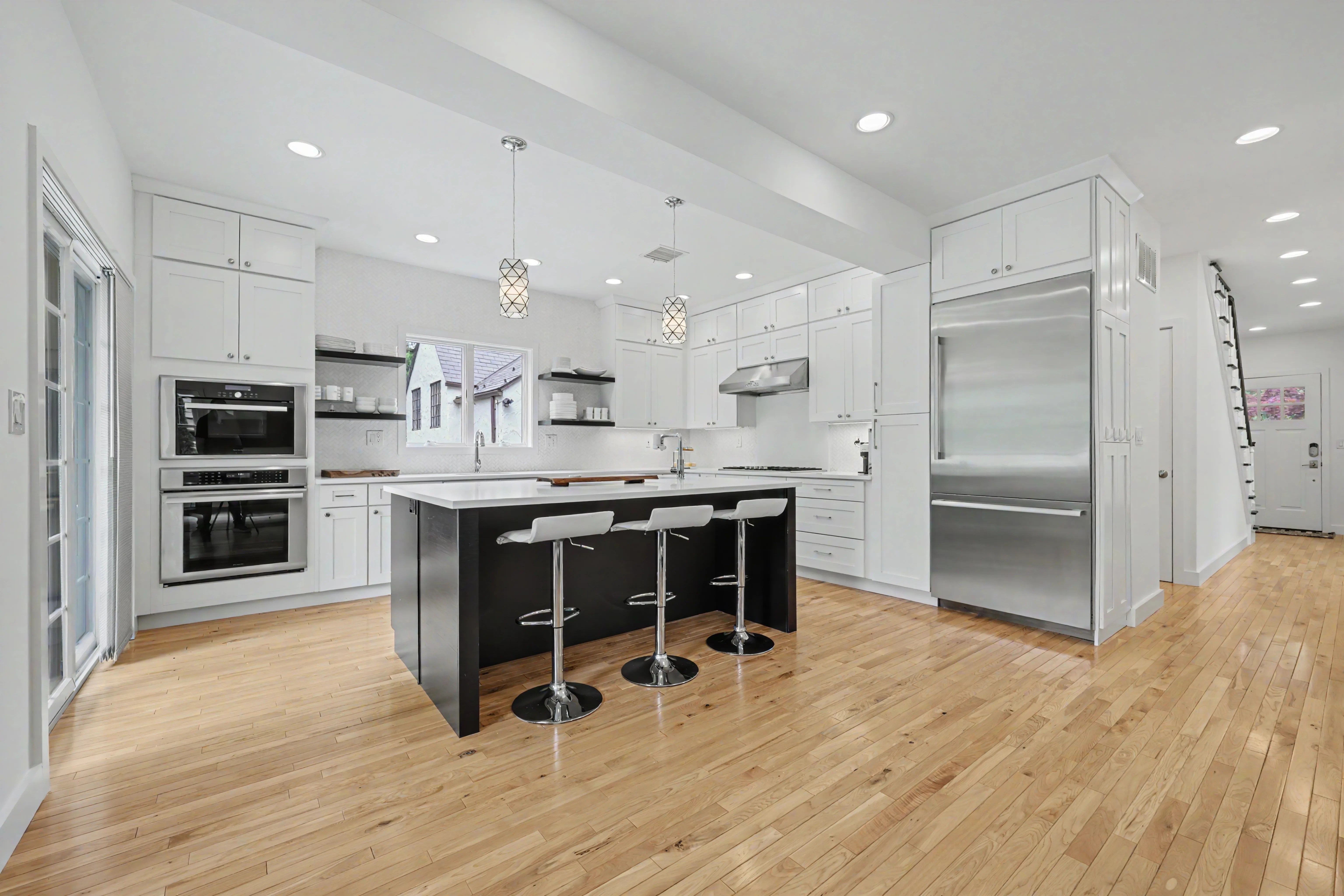 Open-plan kitchen with dark island, pendant lighting, vaulted ceiling, and Sub-Zero refrigerator — real estate photography Westchester County NY